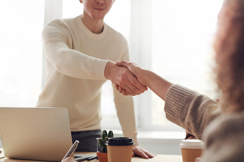 Two professionals shaking hands in a meeting.